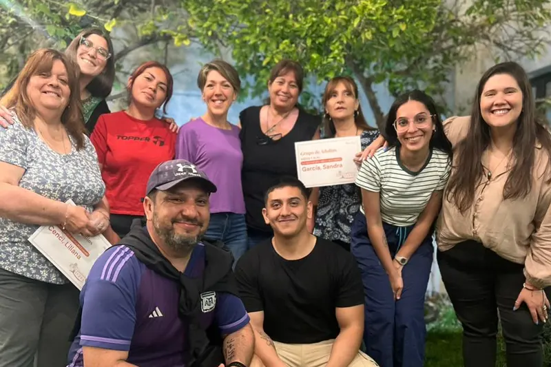 Personas que participaron de un grupo de la fundación, sonrientes en el jardín; una de ellas sostiene su certificado.