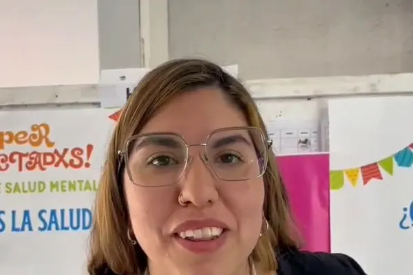 Una integrante del equipo de la fundación en la Kermés de Salud Mental, frente al cartel del evento ¡Hiperconectadxs!