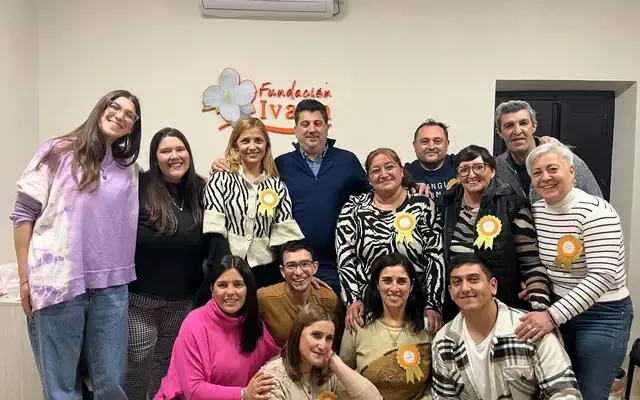 Madres y padres del grupo reunidos en la sala de la fundación, frente al logo de Fundación Ivana.